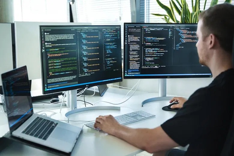 Web developer writing code on dual monitors